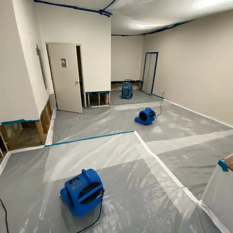 Blue air movers and a dehumidifier in a room with opened lower walls