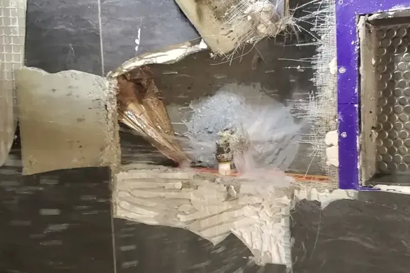 Water spraying from exposed damaged pipework inside an opened wall